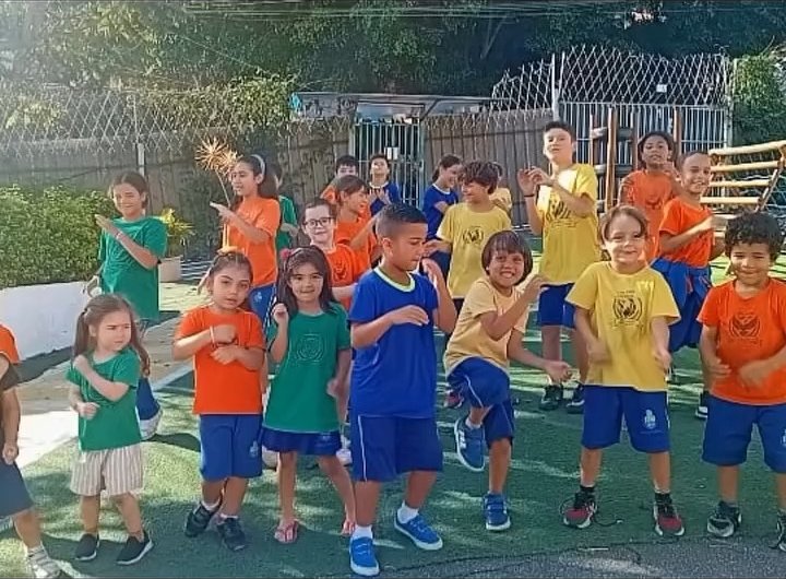 Alunos da Escola Cristal com as camisetas coloridas das casas, brincando na área externa